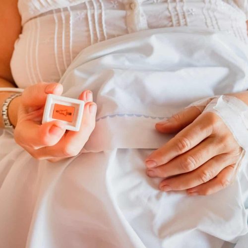 Push button to call a nurse in a hospital, pressed by a patient in her bed.